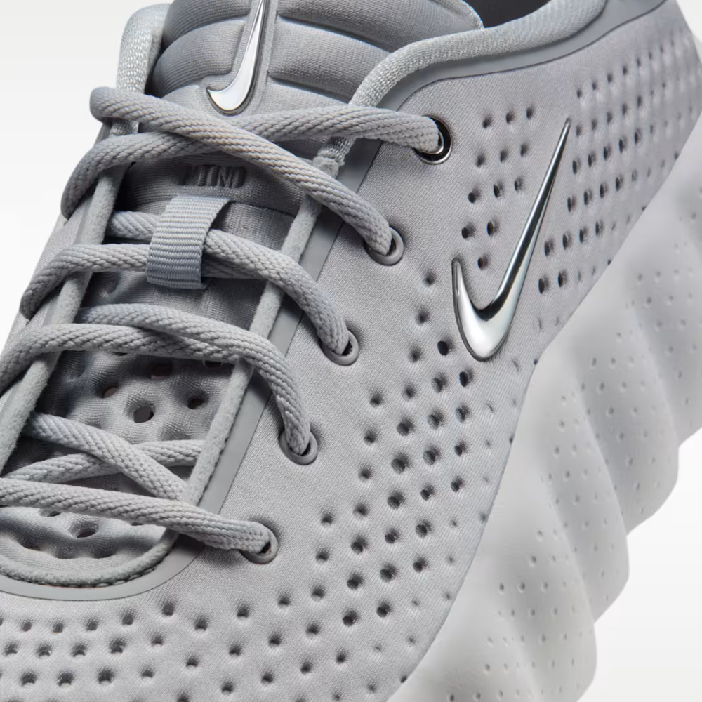 Detalle del frente Nike Mind 002 - logo Swoosh metálico y parte superior perforada color gris claro