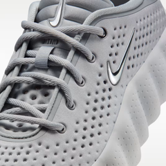 Detalle del frente Nike Mind 002 - logo Swoosh metálico y parte superior perforada color gris claro